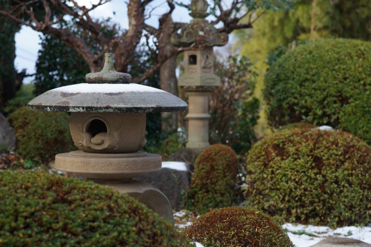 日本庭園に雪見灯篭と春日灯篭が置かれている写真