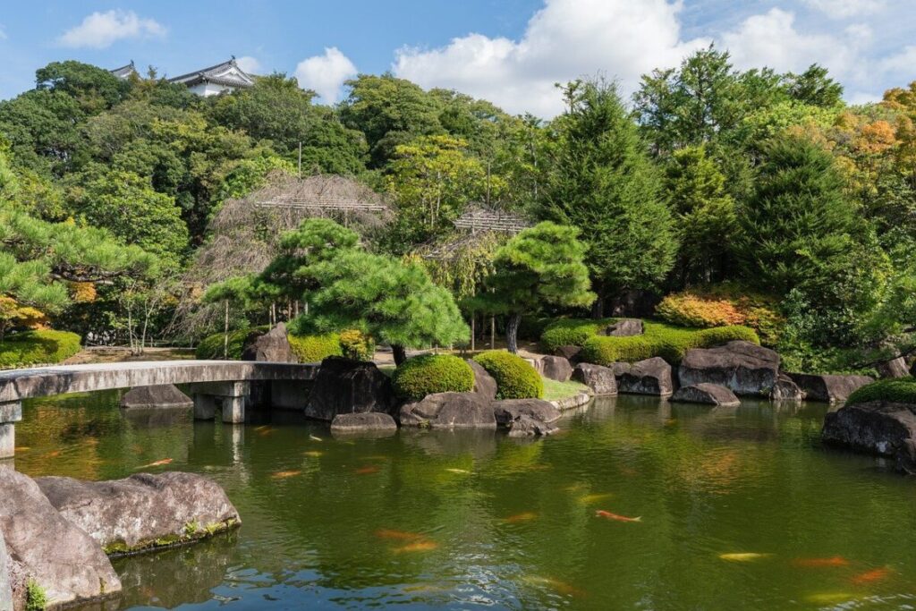 大きな池に鯉が泳いでいる池泉庭園の写真