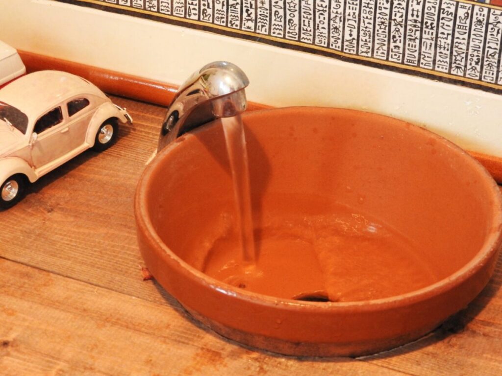 トイレに置かれた茶系の手洗い鉢の写真