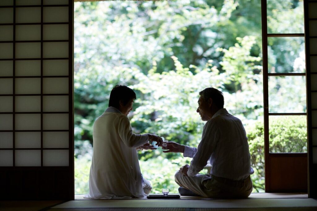 縁側で夫婦が据わっている和風住宅の写真