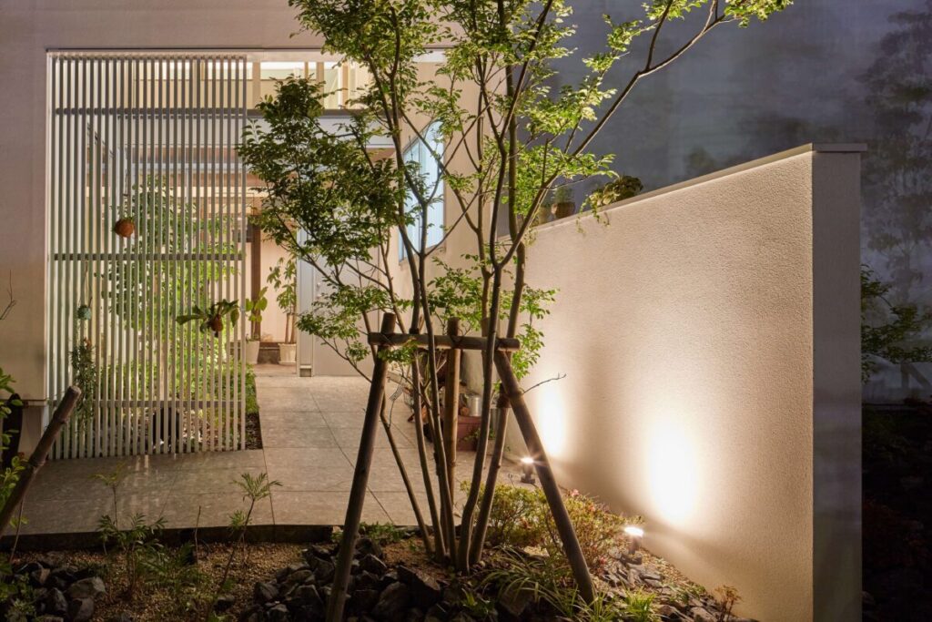 和モダン住宅の玄関の壁をガーデンライトで照らしている画像
