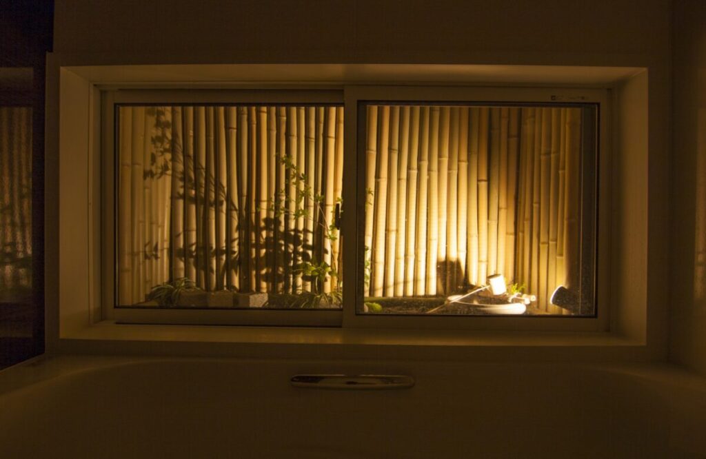 お風呂から眺めるライトアップされた竹垣で囲われた坪庭写真