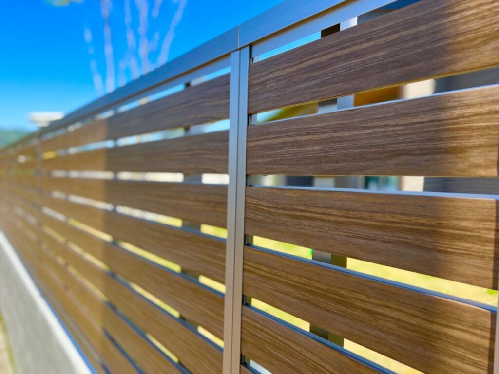 隙間の空いた木目調の人工フェンスを斜めからアップしている写真