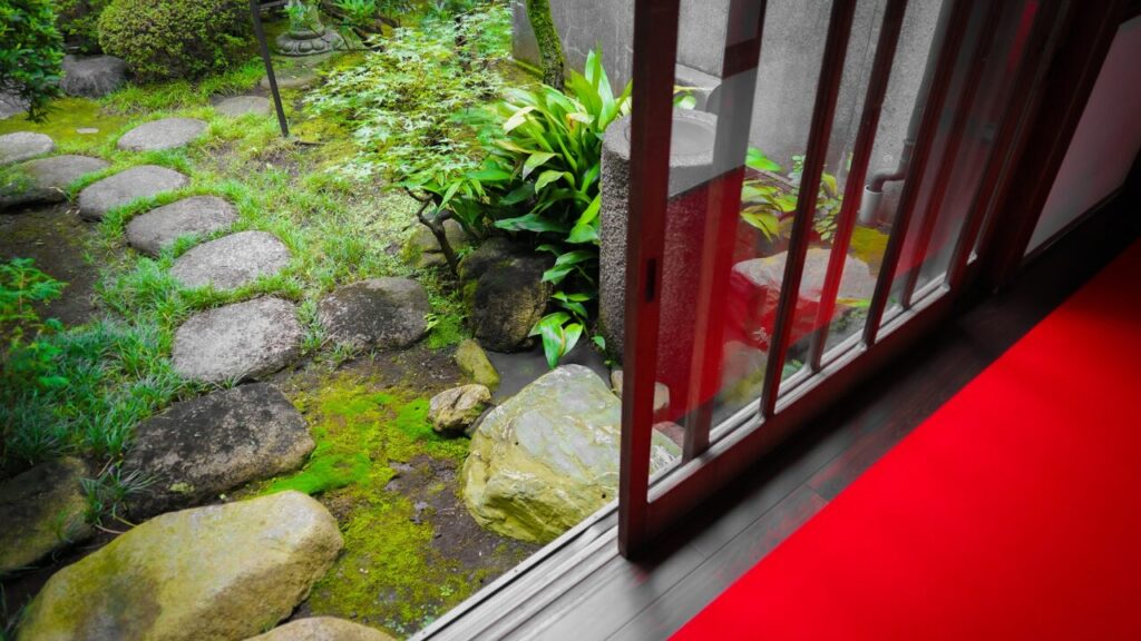 和風の家から臨む下草、芝生が植えてあり、自然形の飛び石が置かれている和風庭の画像