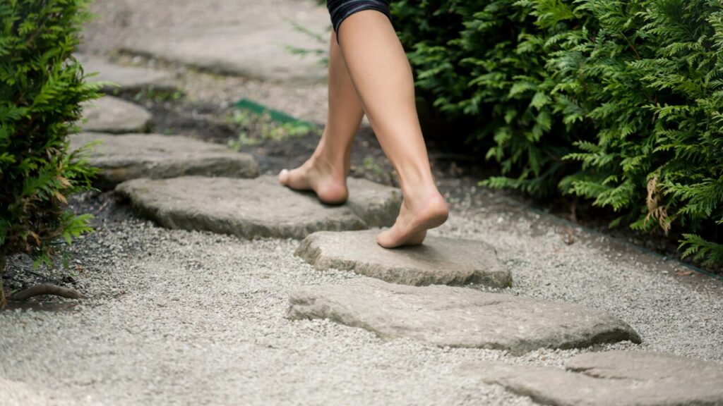 白砂と天然石の飛び石を人がはだしで歩いている写真